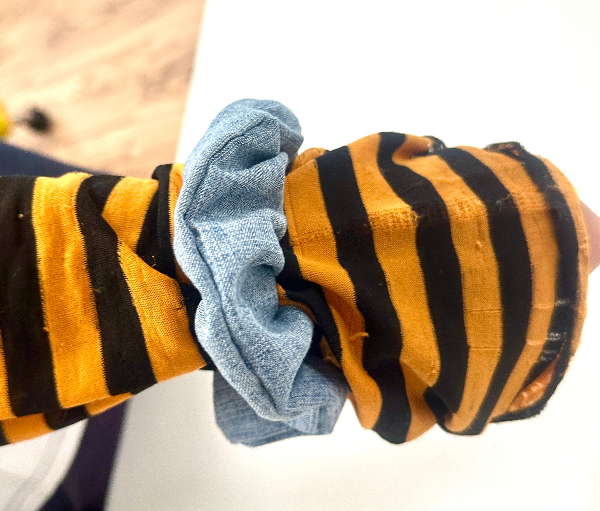 A blue denim scrunchie worn on a wrist