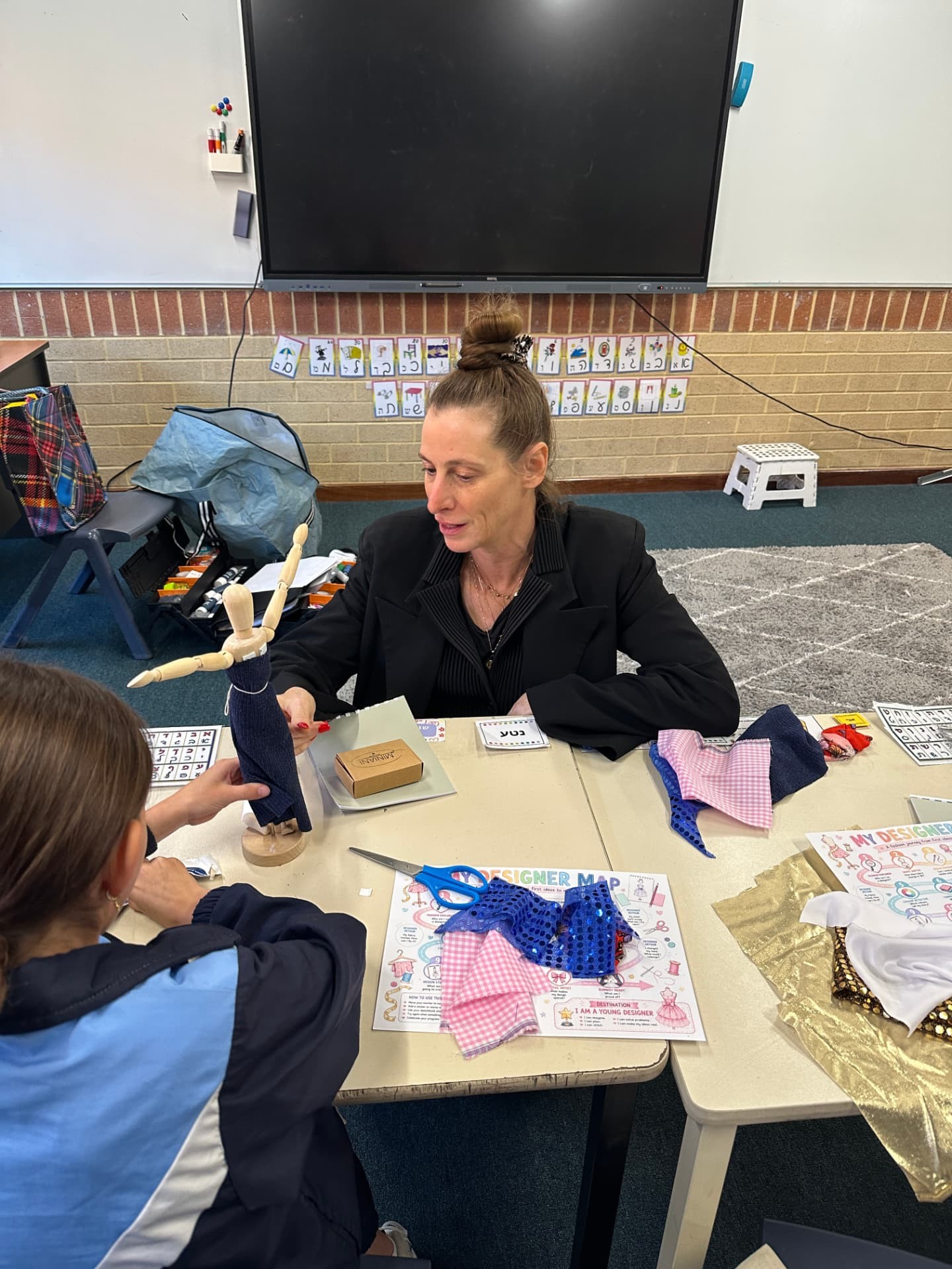 A MINIANI instructor helping a young designer with a sewing project