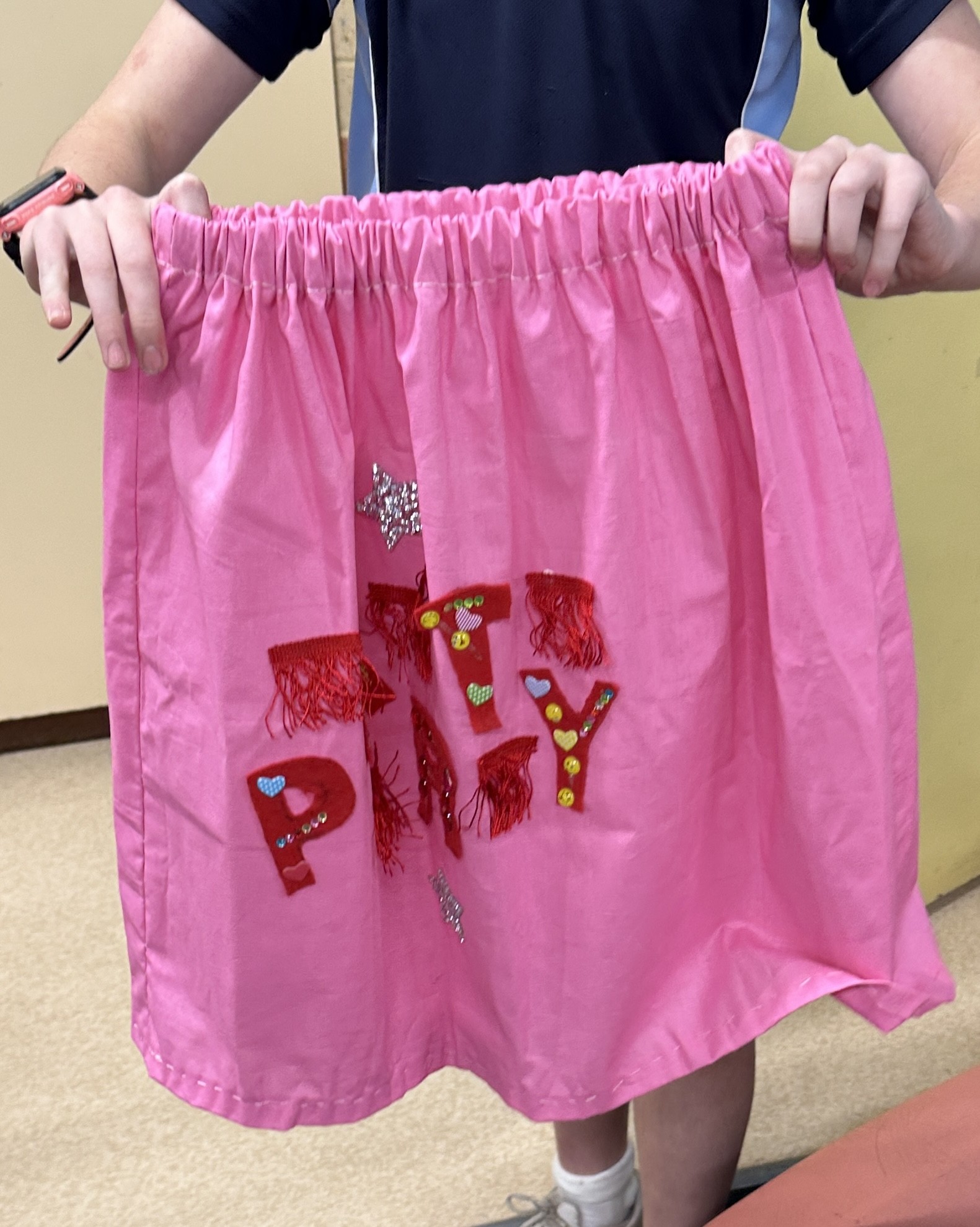 A young maker displaying a pink handmade skirt
