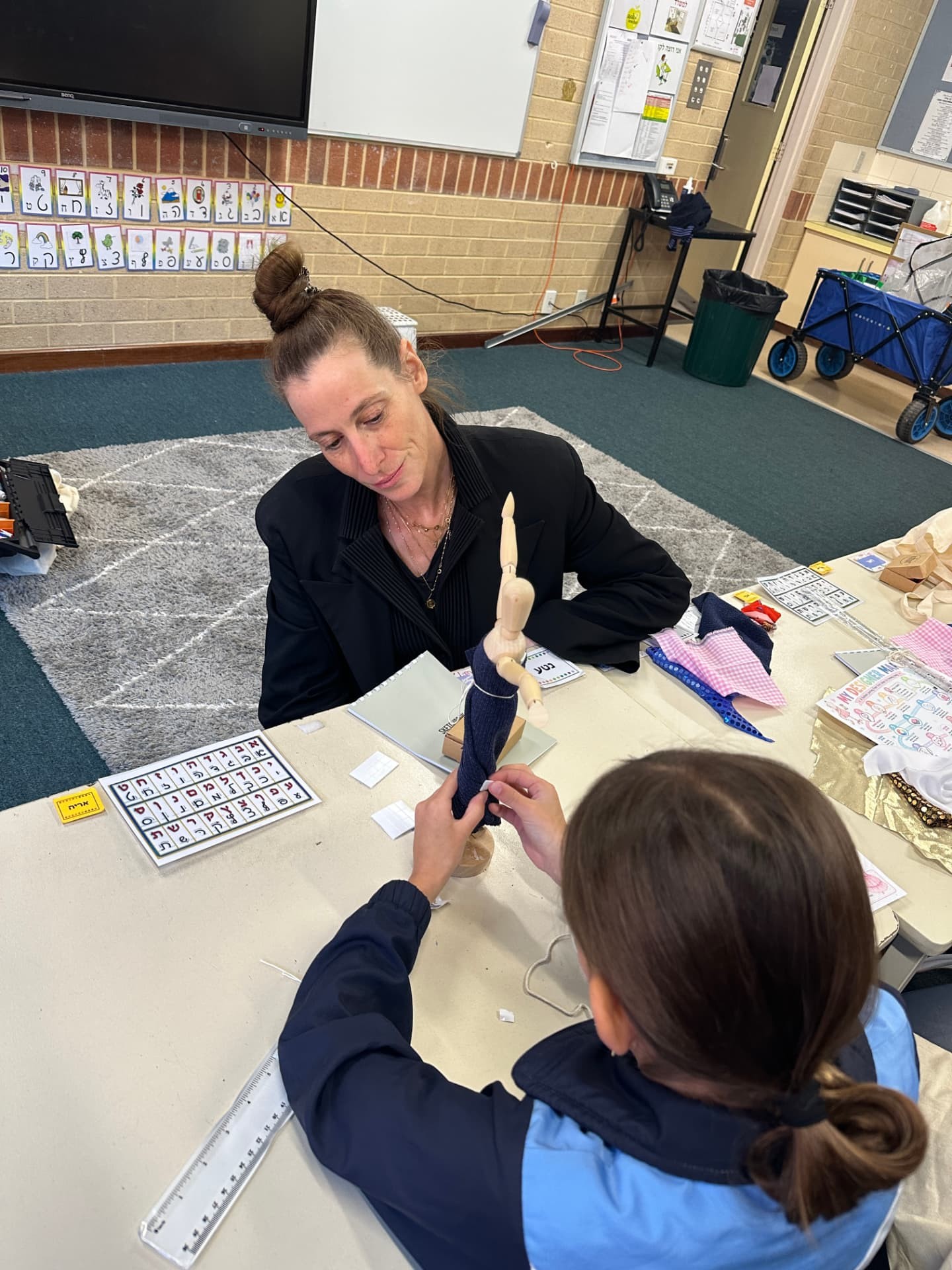 An instructor guiding a student through hand sewing